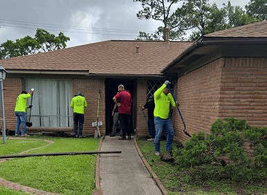 Workers cleaning outside a brick house