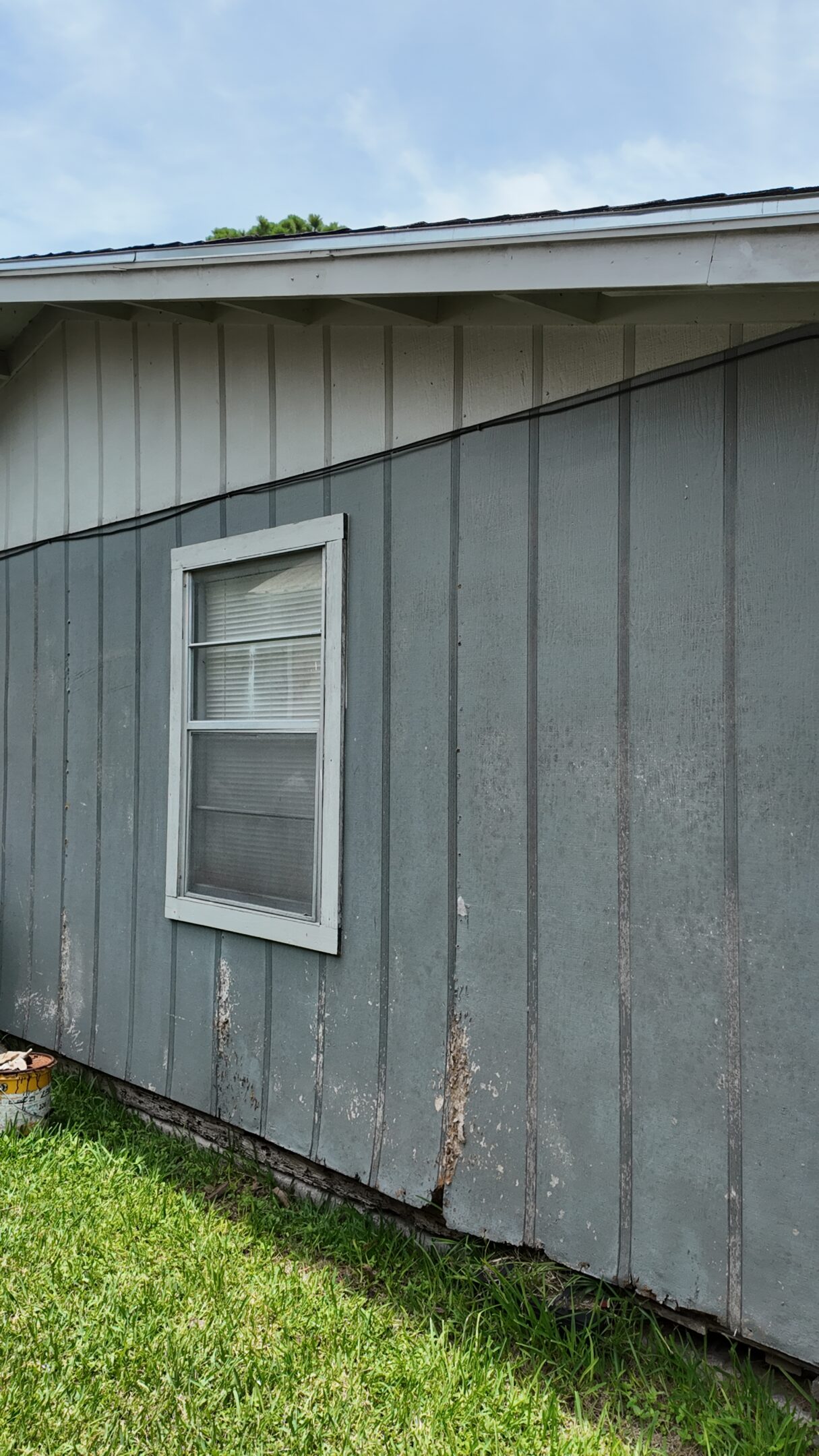 A grey wooden exterior wall with a small window.