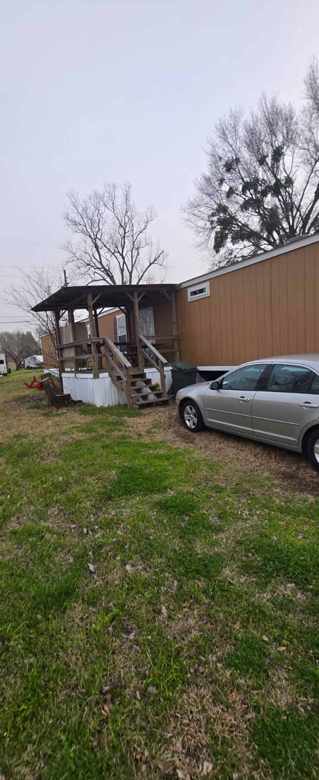 A silver car parked next to a small brown building with a porch.