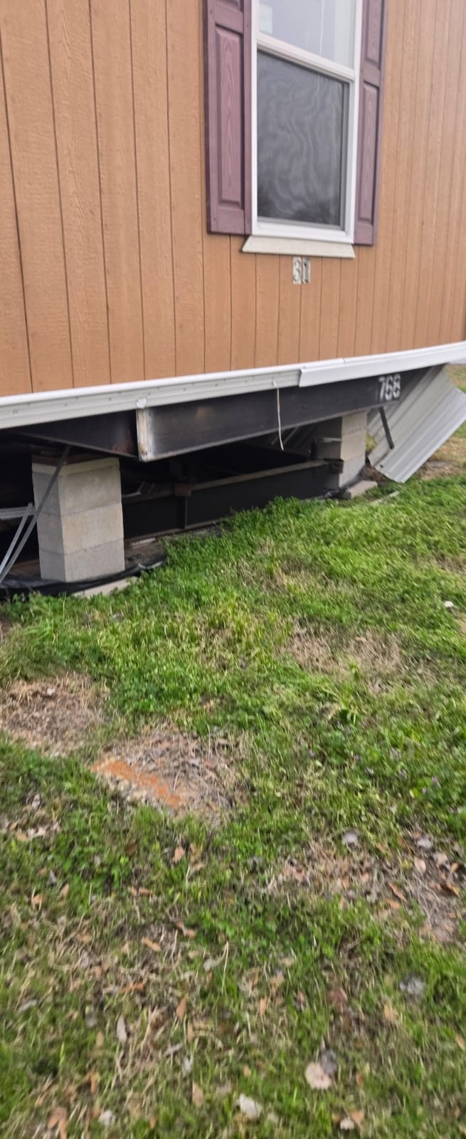 Concrete blocks supporting a structure above grassy ground.