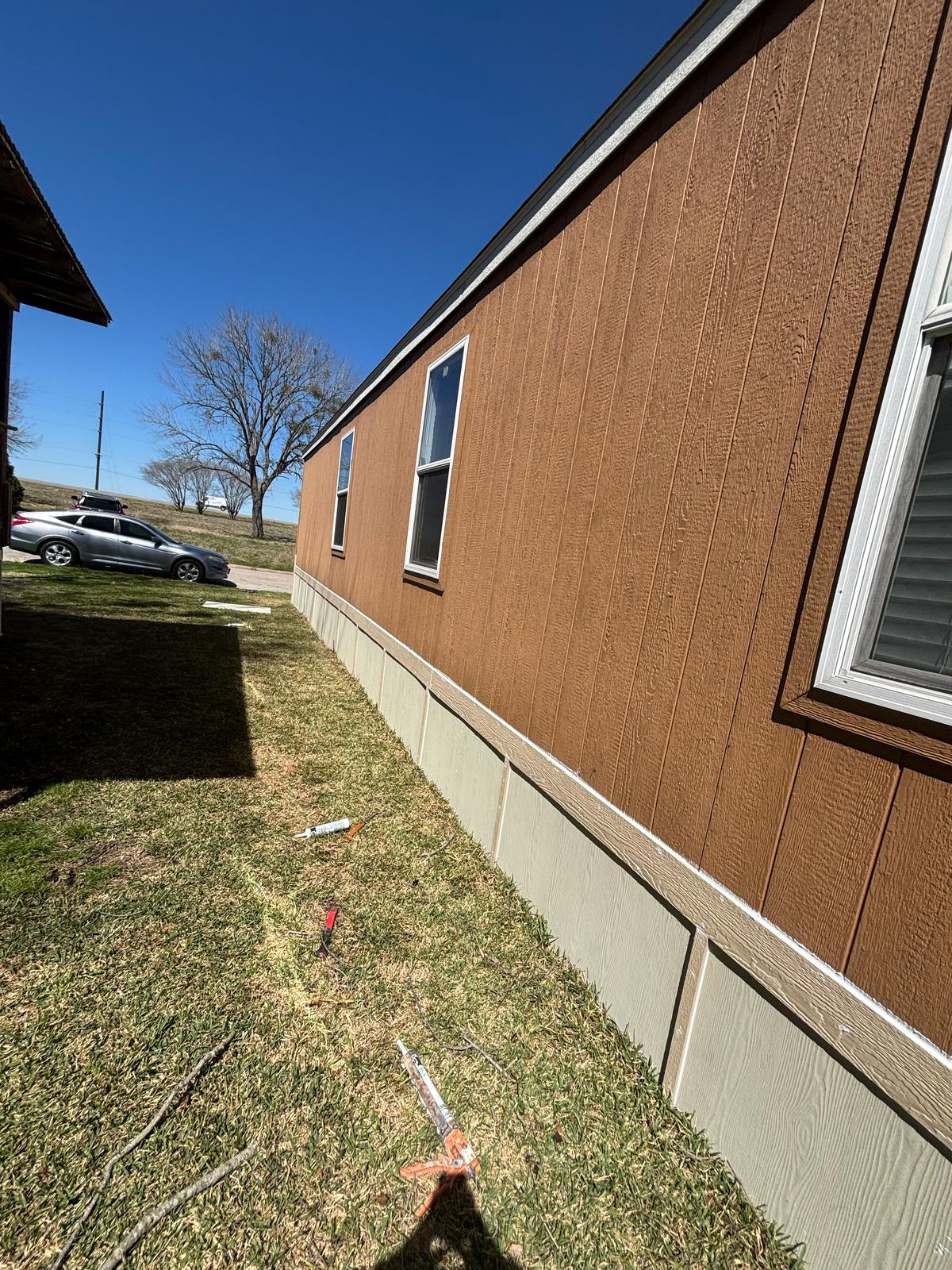 Side view of a brown house with windows and grass.
