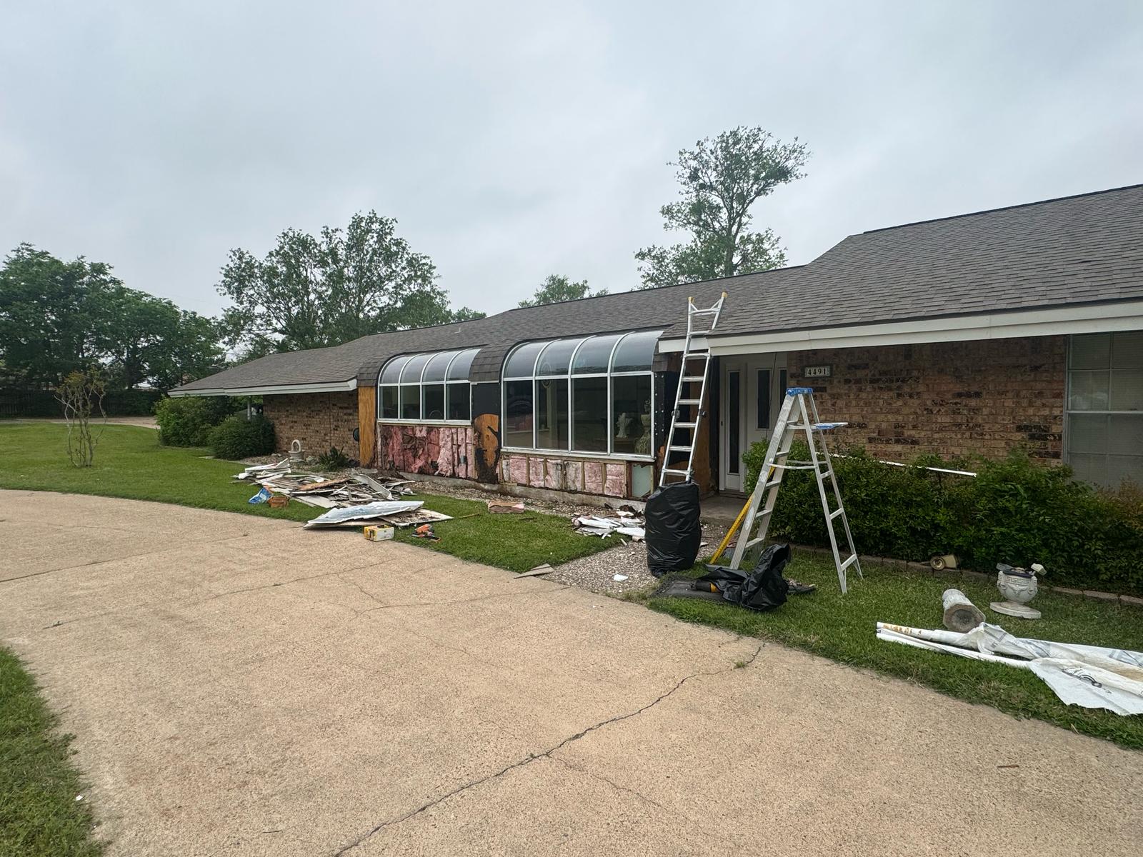 Home exterior renovation with ladders and materials scattered around.