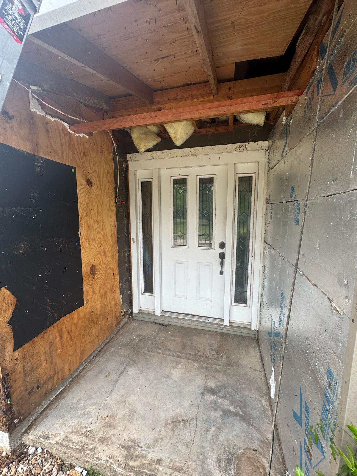 White double doors at the end of a partially renovated hallway.