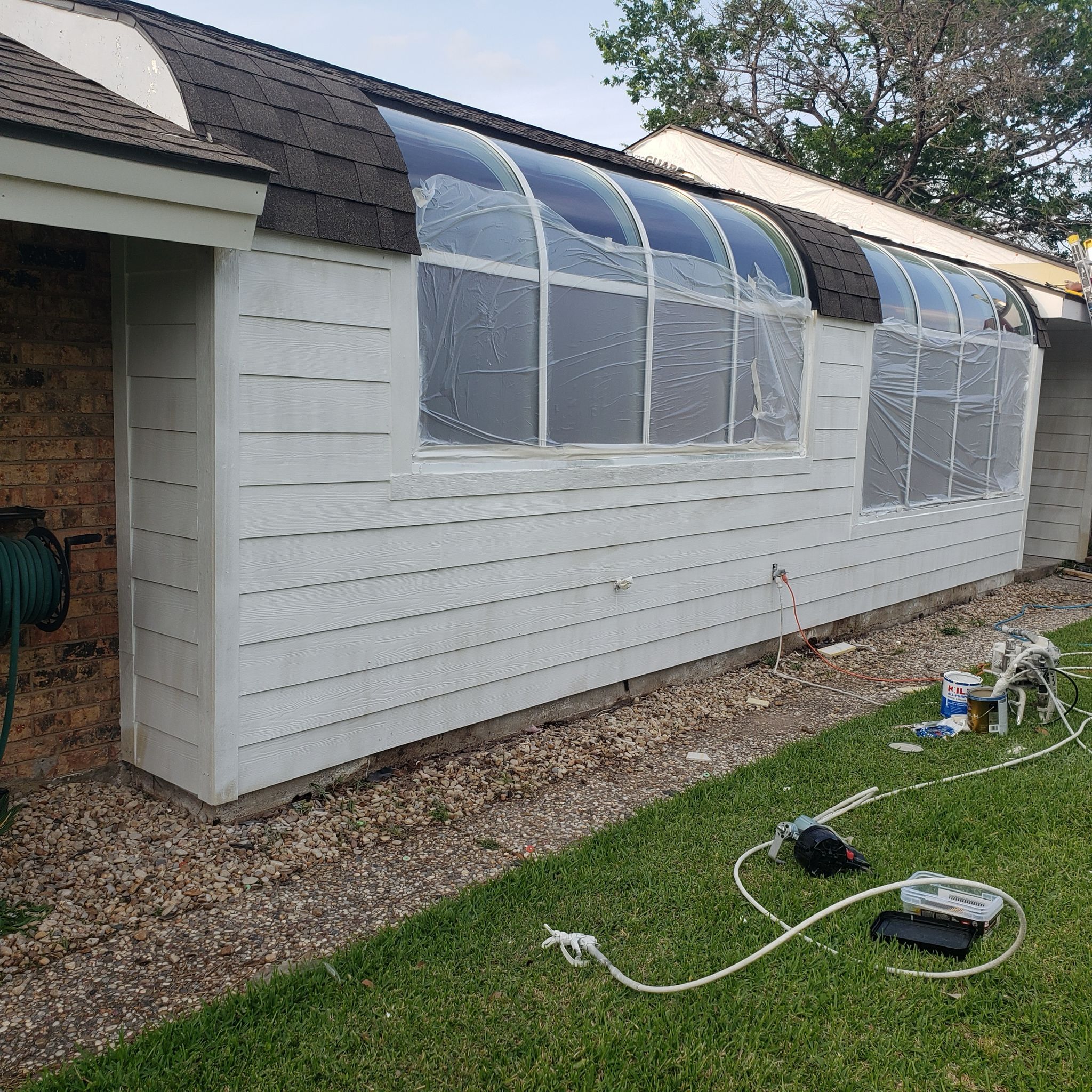 A white greenhouse attached to a shed with curved roof windows.
