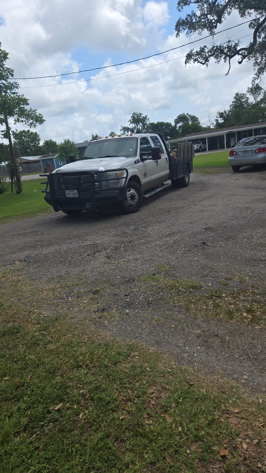 A white utility truck parked on a gravel driveway near a grassy area.