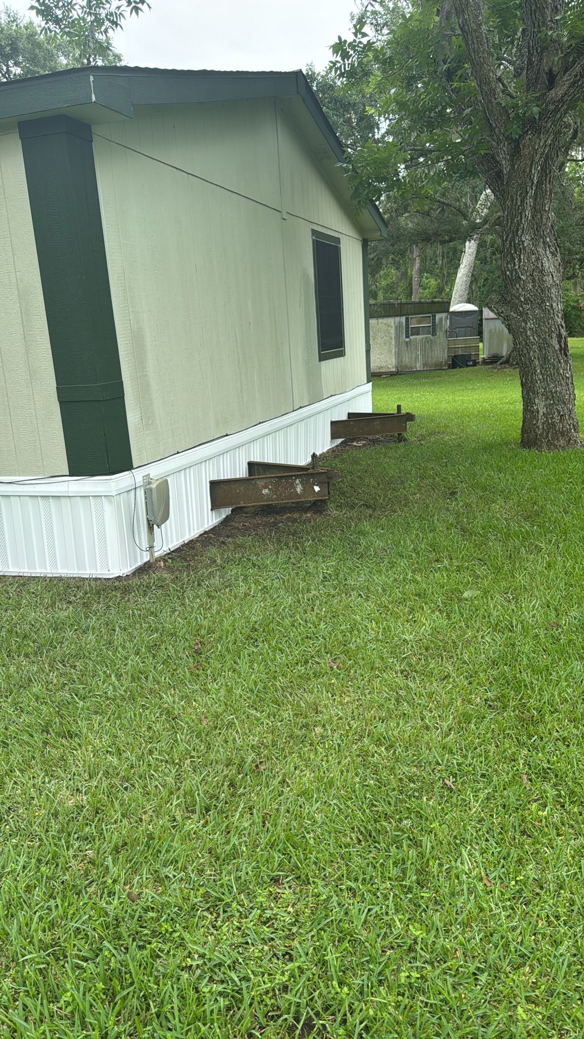 Two small wooden steps lead to mobile homes on a green lawn.