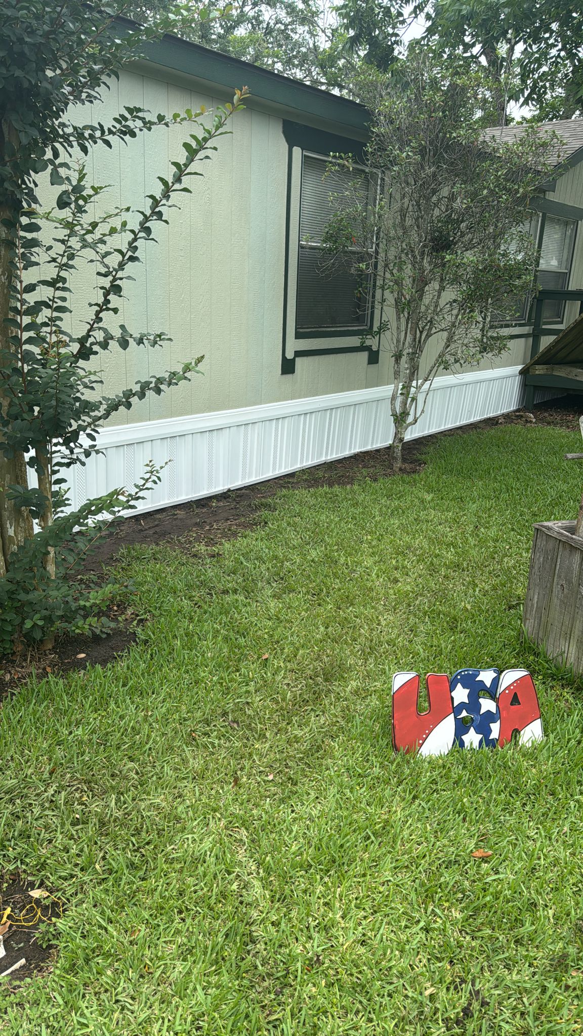 A small patriotic-themed mailbox in front of a mobile home.
