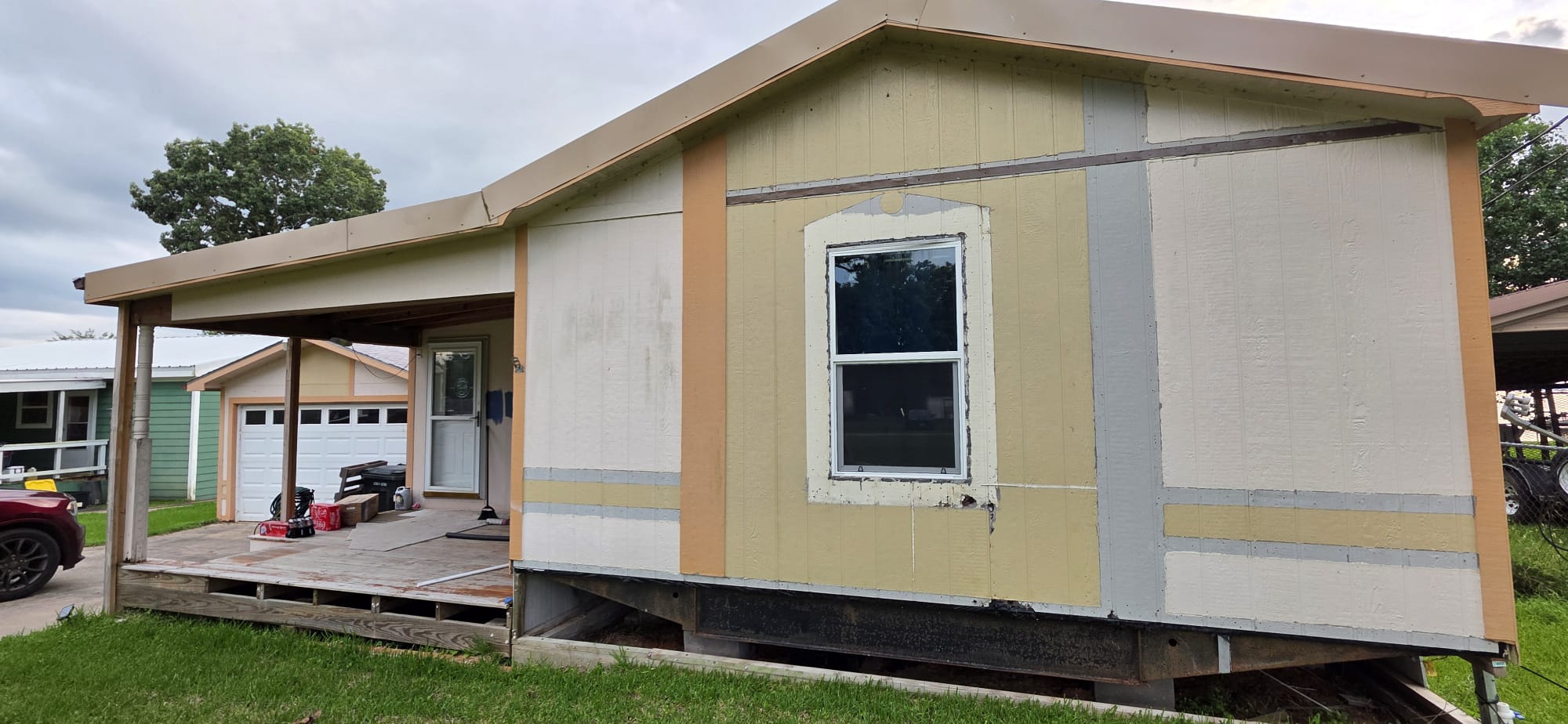 Side view of a house exterior with a single window and patchy paint.