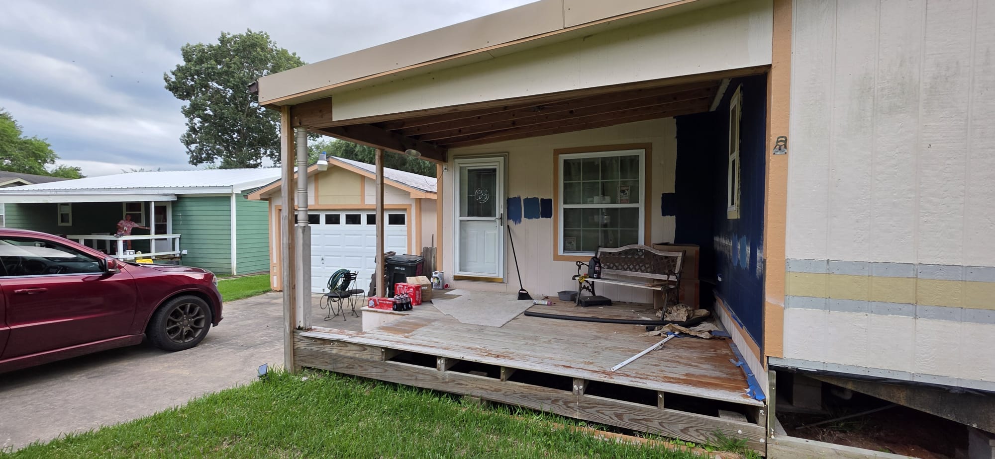 Back porch with worn wooden floor and outdoor furniture under a roof.