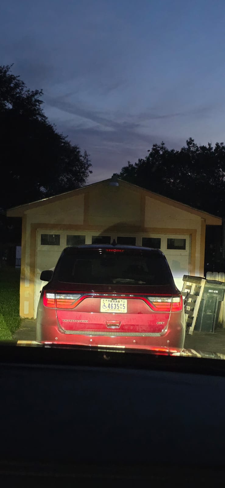 A red SUV parked in front of a yellow garage at night.
