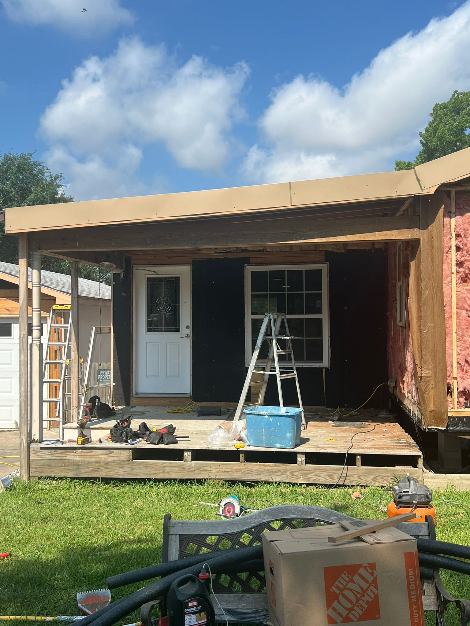 House under construction with scaffolding and tools on the porch.