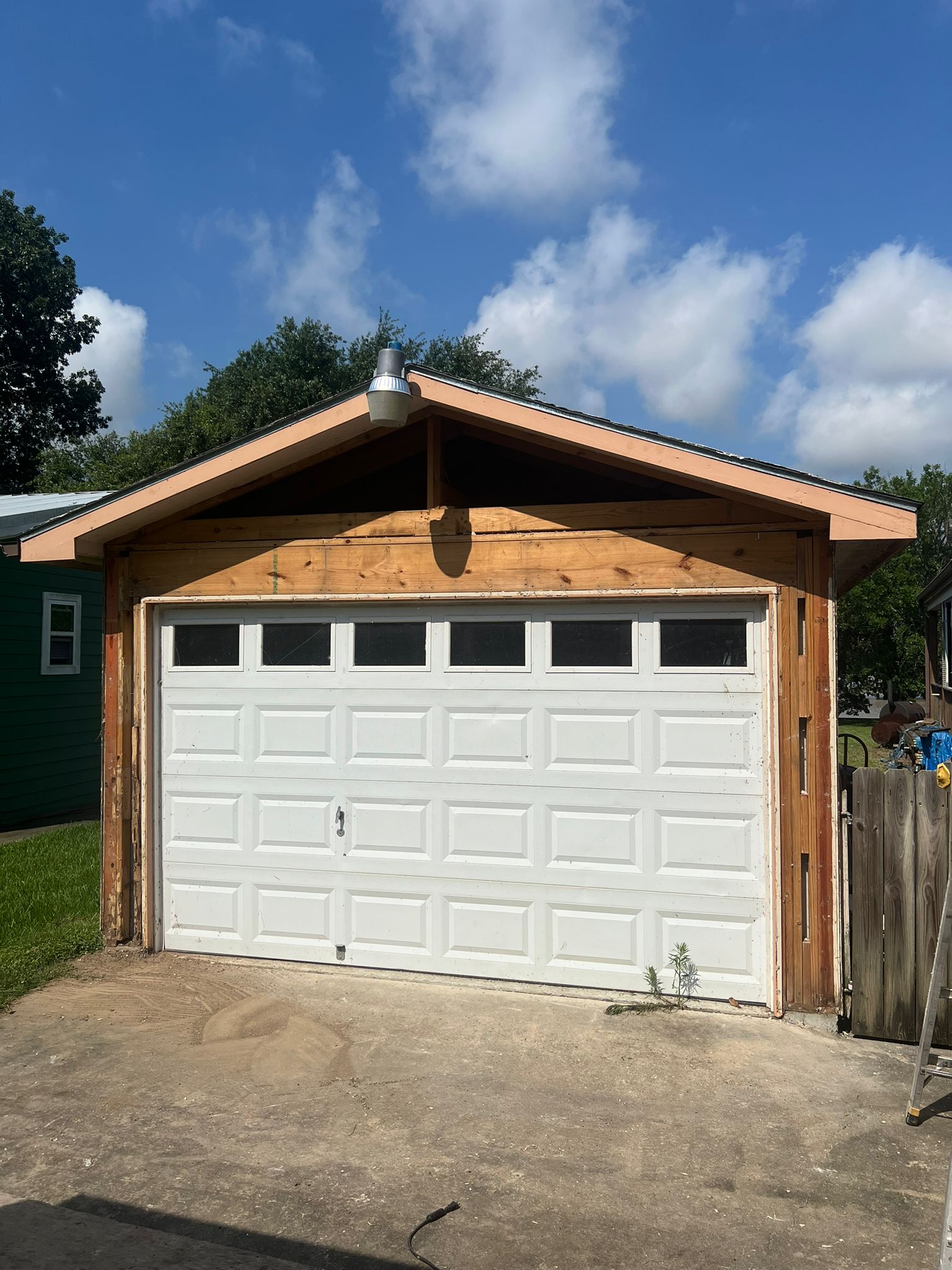 A white garage door on a wooden house with a triangular roof.