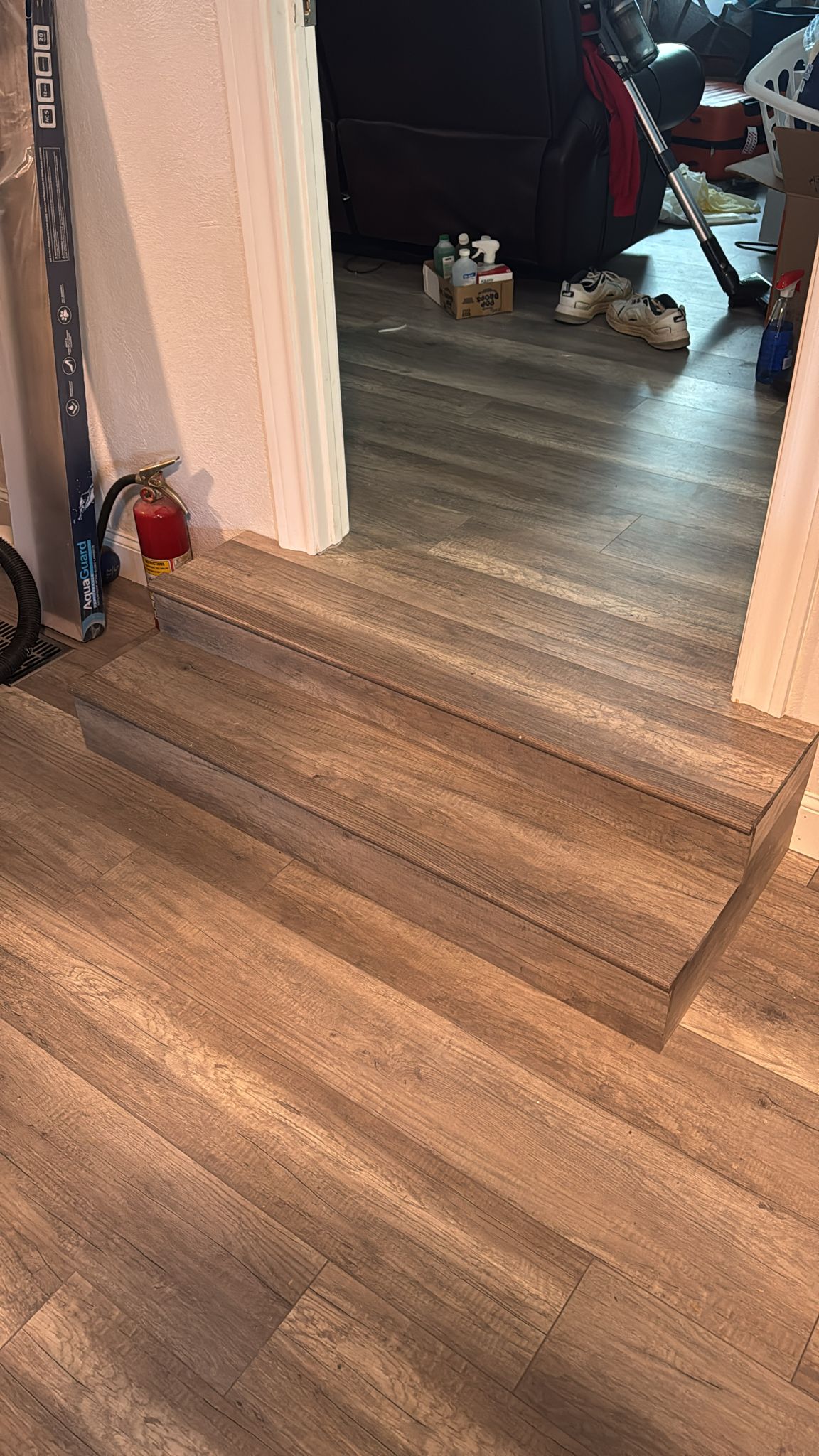 Wooden flooring with an uneven step transition between two rooms.