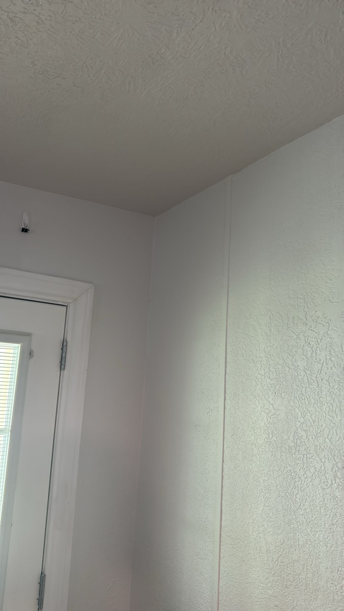 A photo of a plain white wall corner and a door frame.