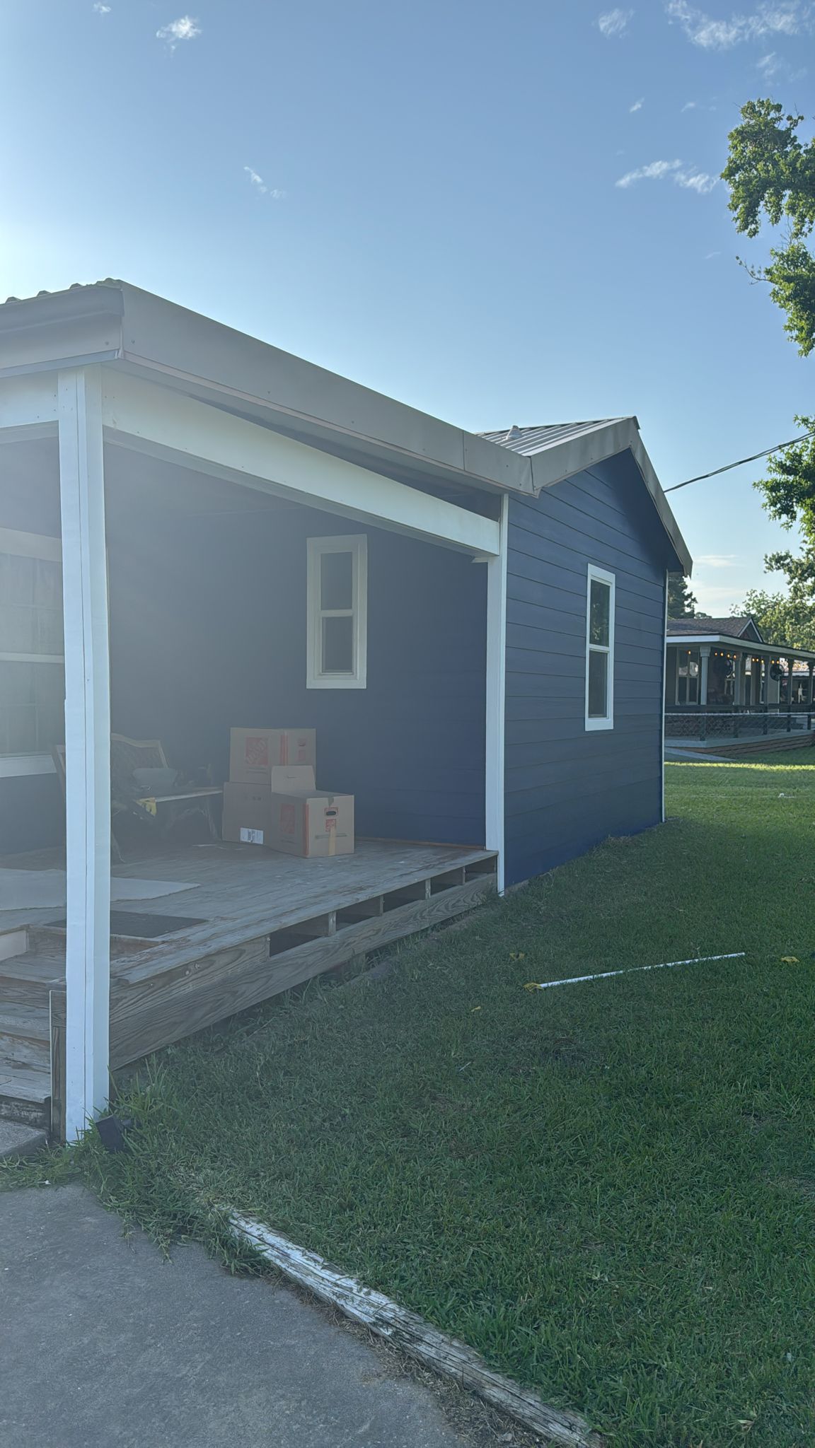 A small blue house with a porch and cardboard boxes on it.