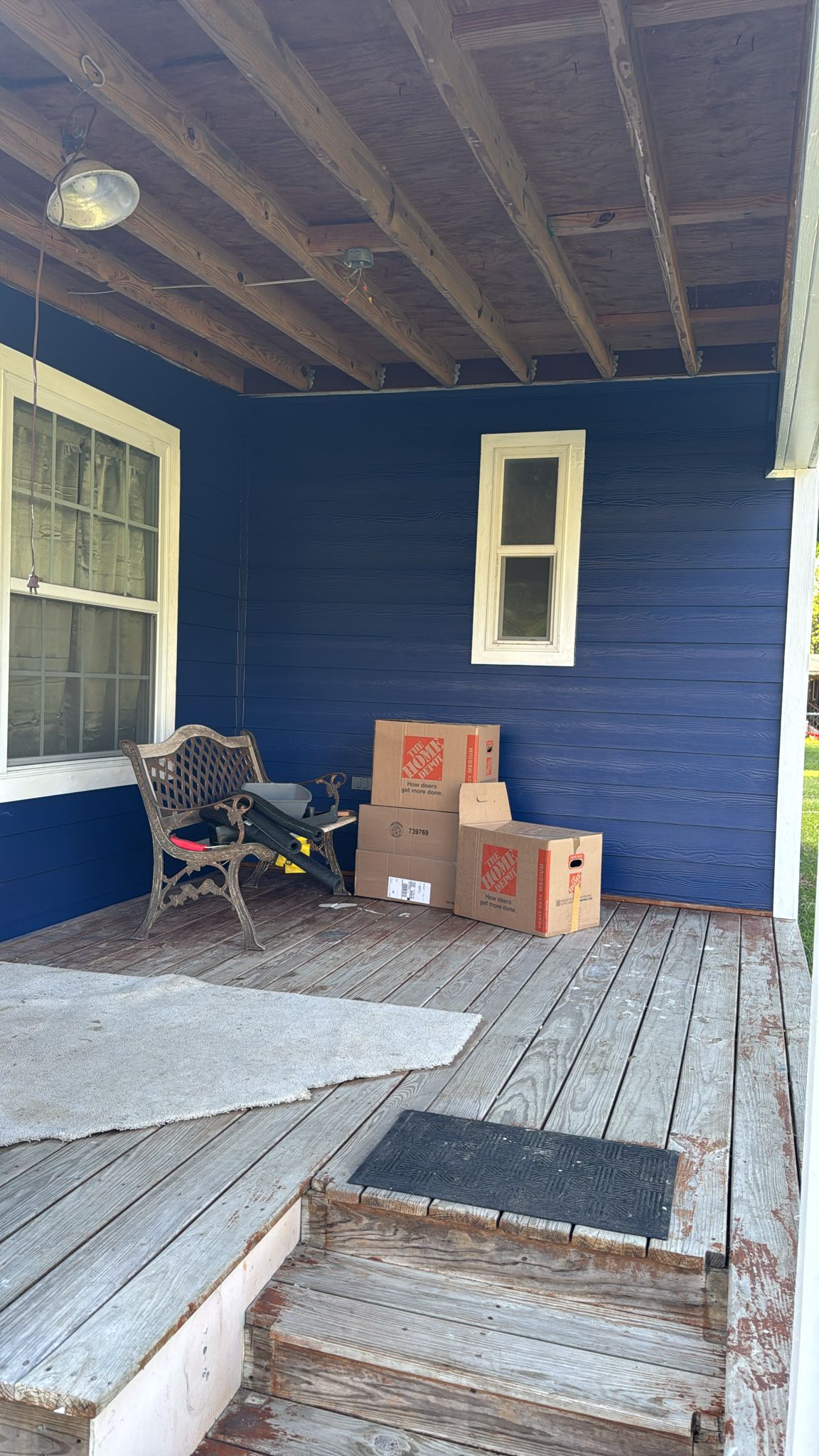 Front porch with stacked cardboard boxes and a bench.