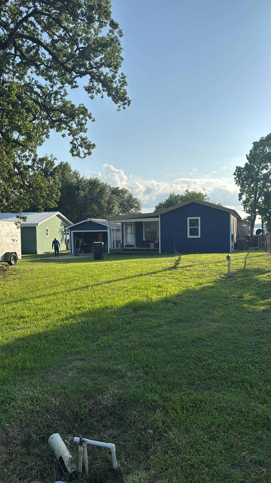 A sunny backyard with two small houses and a green lawn.