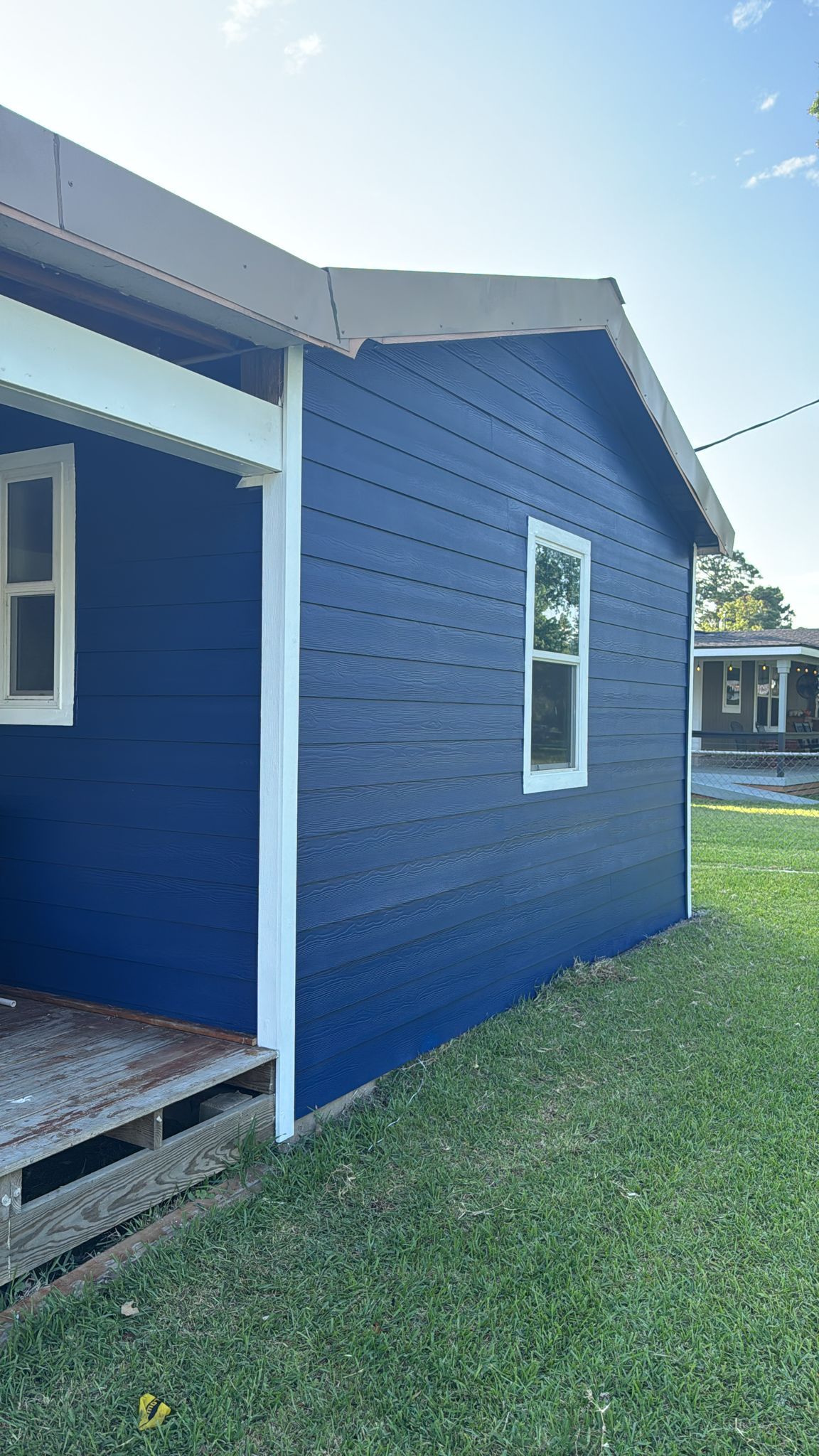 Blue house exterior with white-trimmed windows on green lawn.