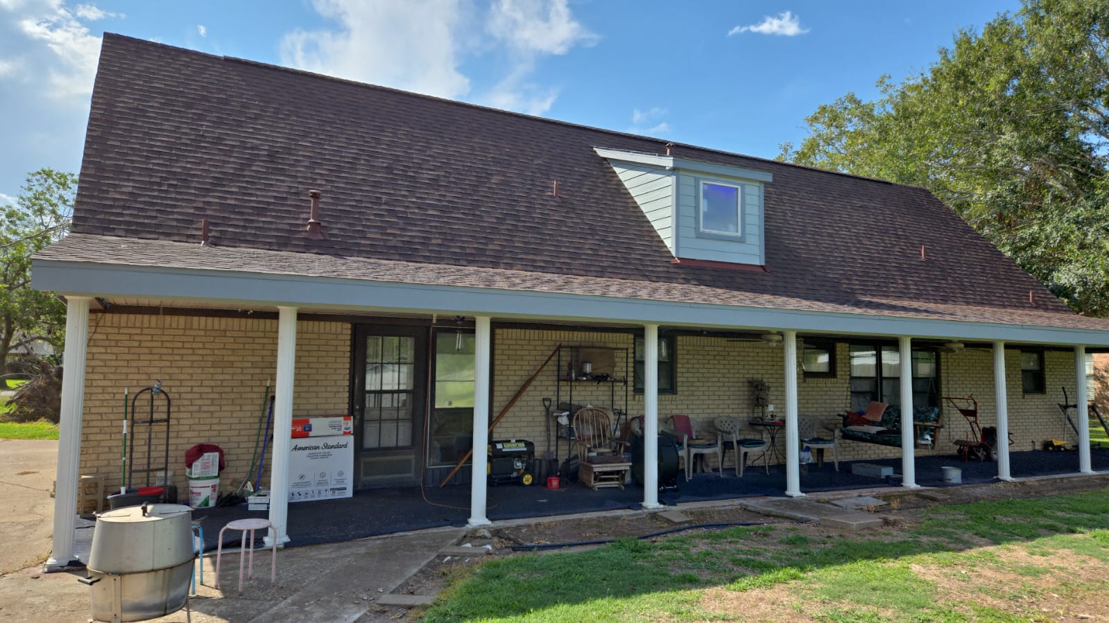 Front porch of a house with various items and a bench under a sloped roof.