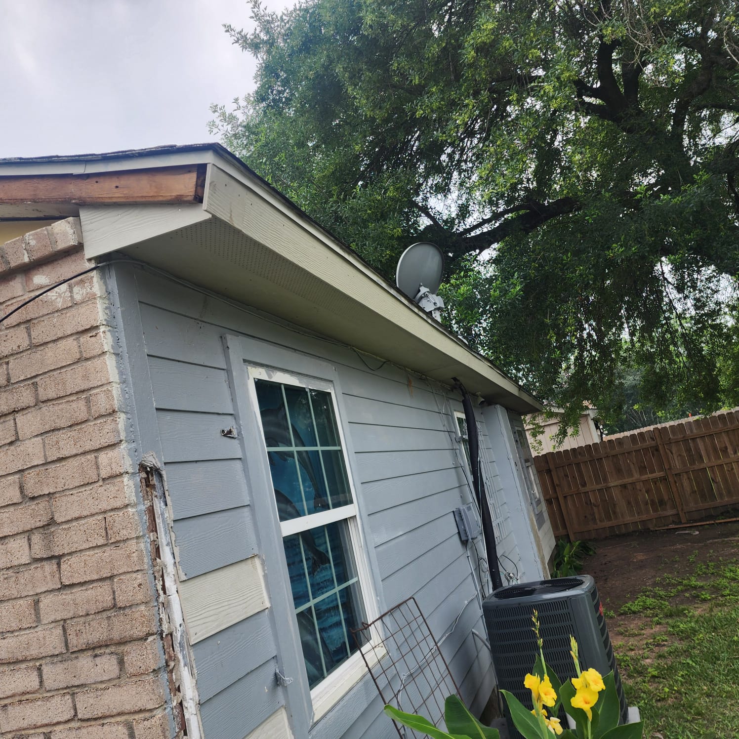 Side view of a house with brick and siding exterior under a partly cloudy sky.