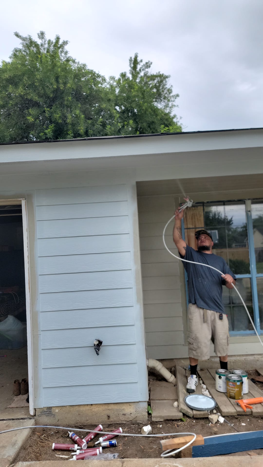 Man power washing the exterior wall of a house.