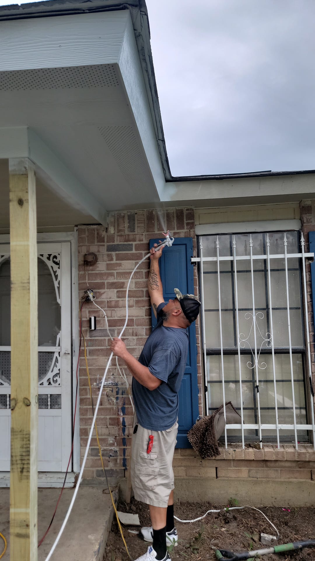 Man installing or adjusting an outdoor device on a brick wall.