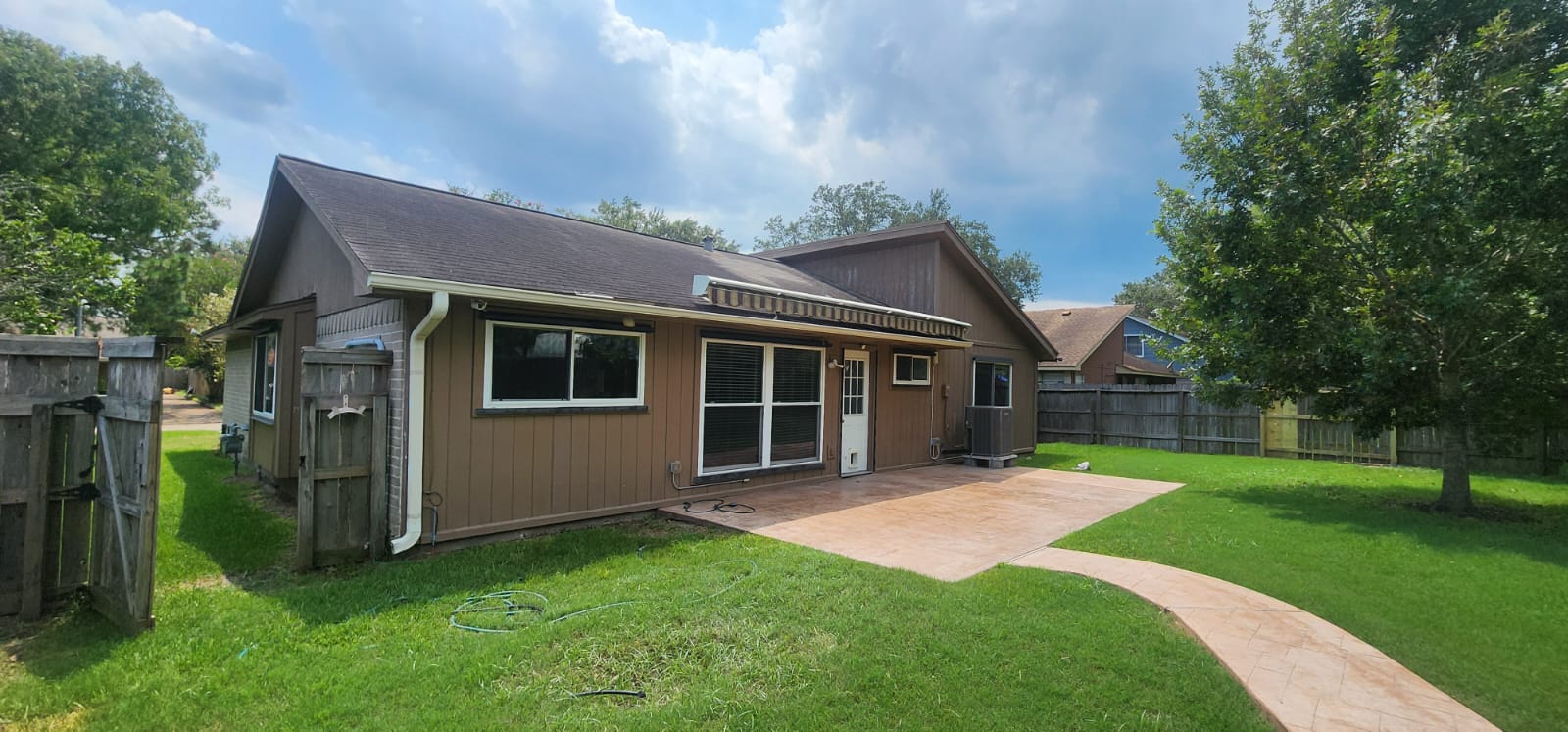 Modern brown house with large windows and a spacious lawn.