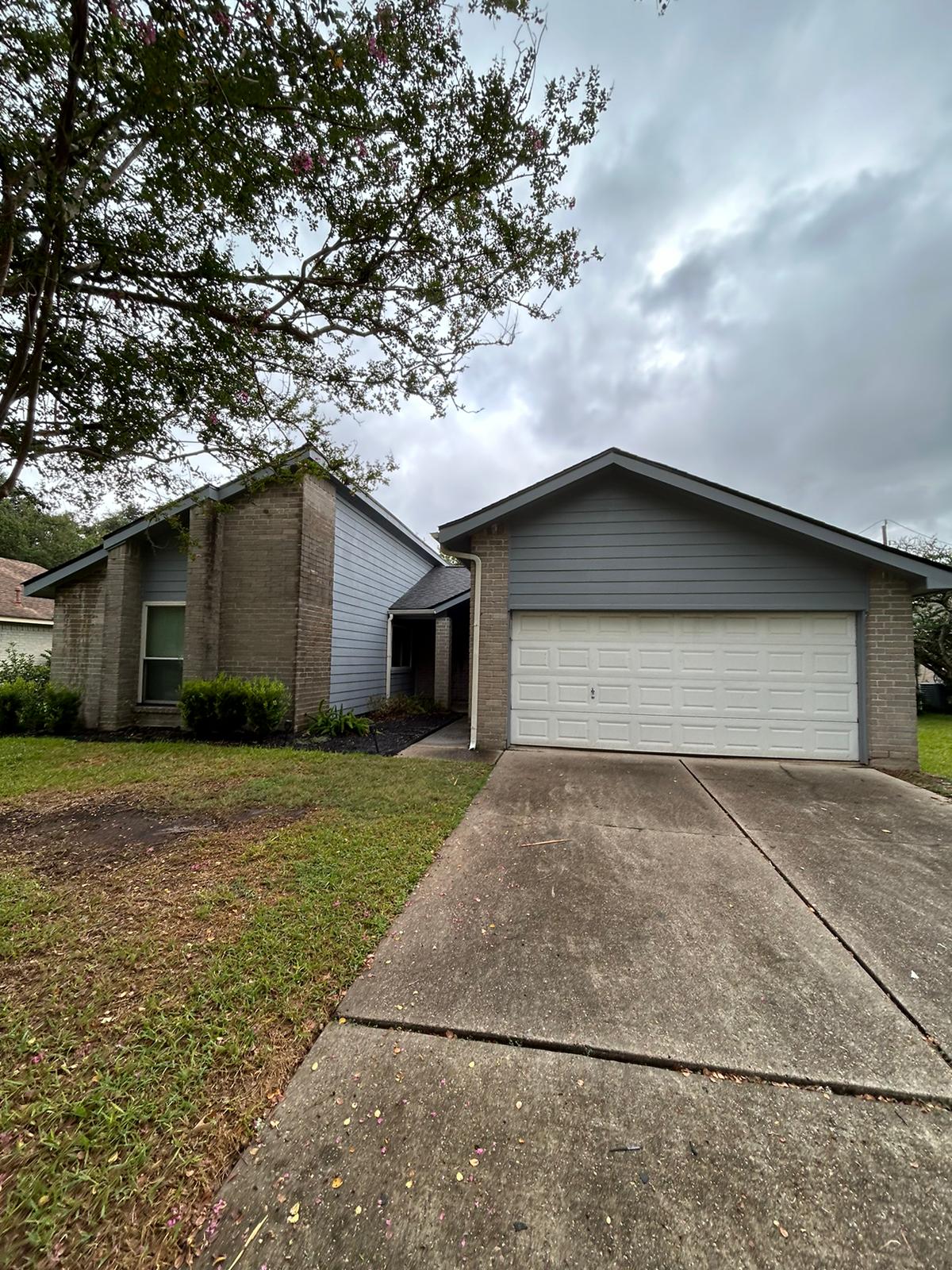 A suburban house with a two-car garage under an overcast sky.
