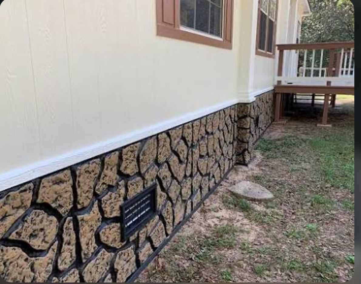 House exterior with stone-patterned lower wall and small vent.