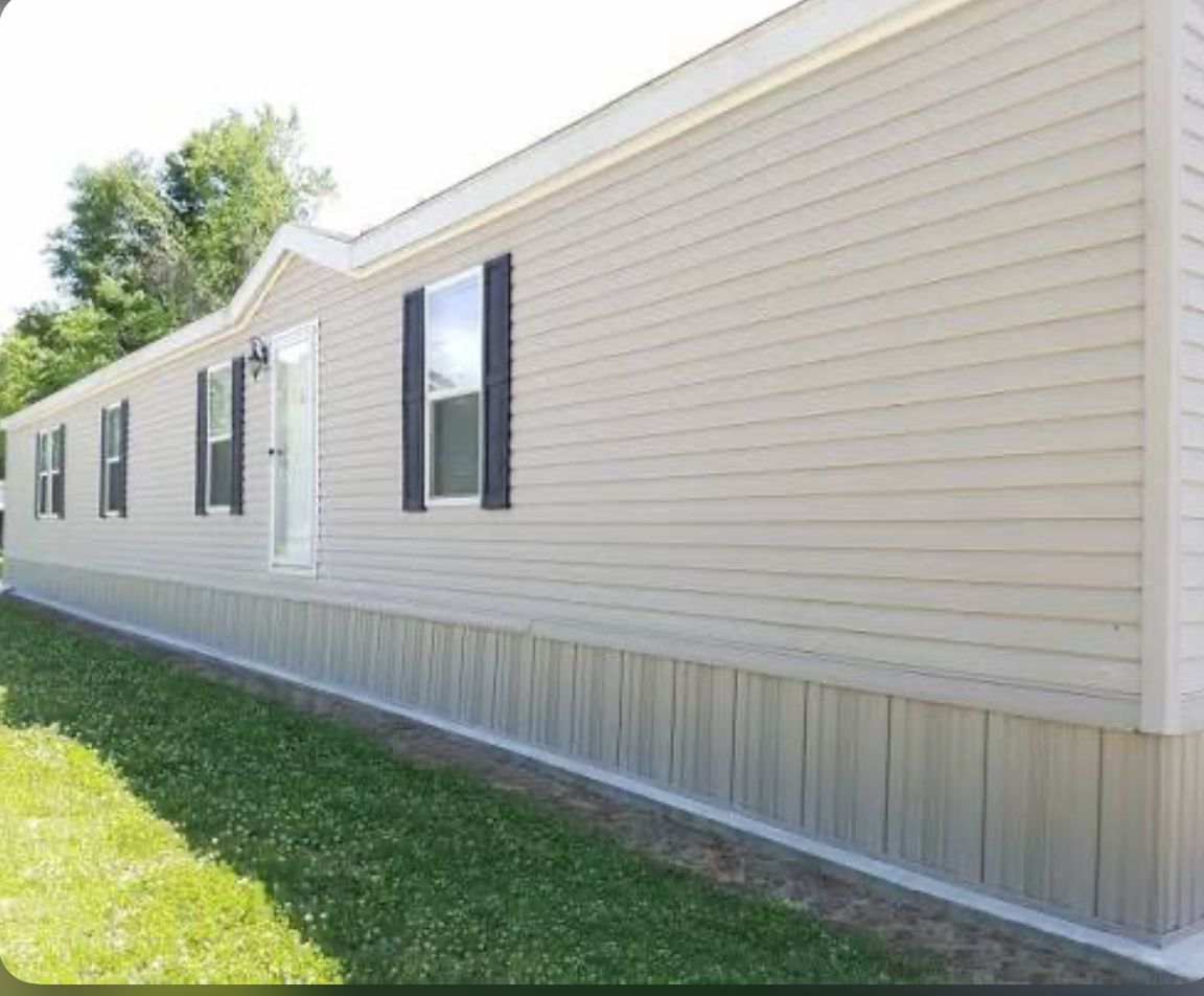 Side view of a beige mobile home with black window shutters.