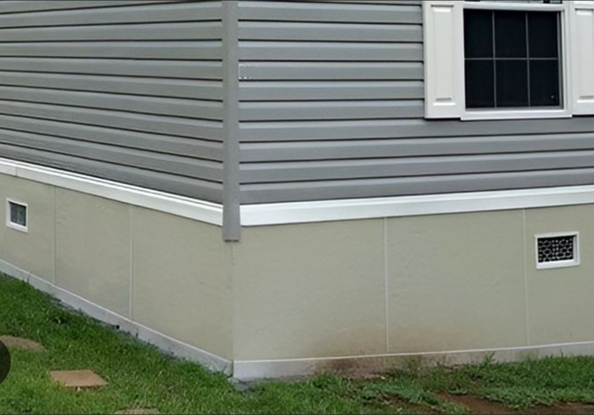 Siding and foundation of a house with grass around it.