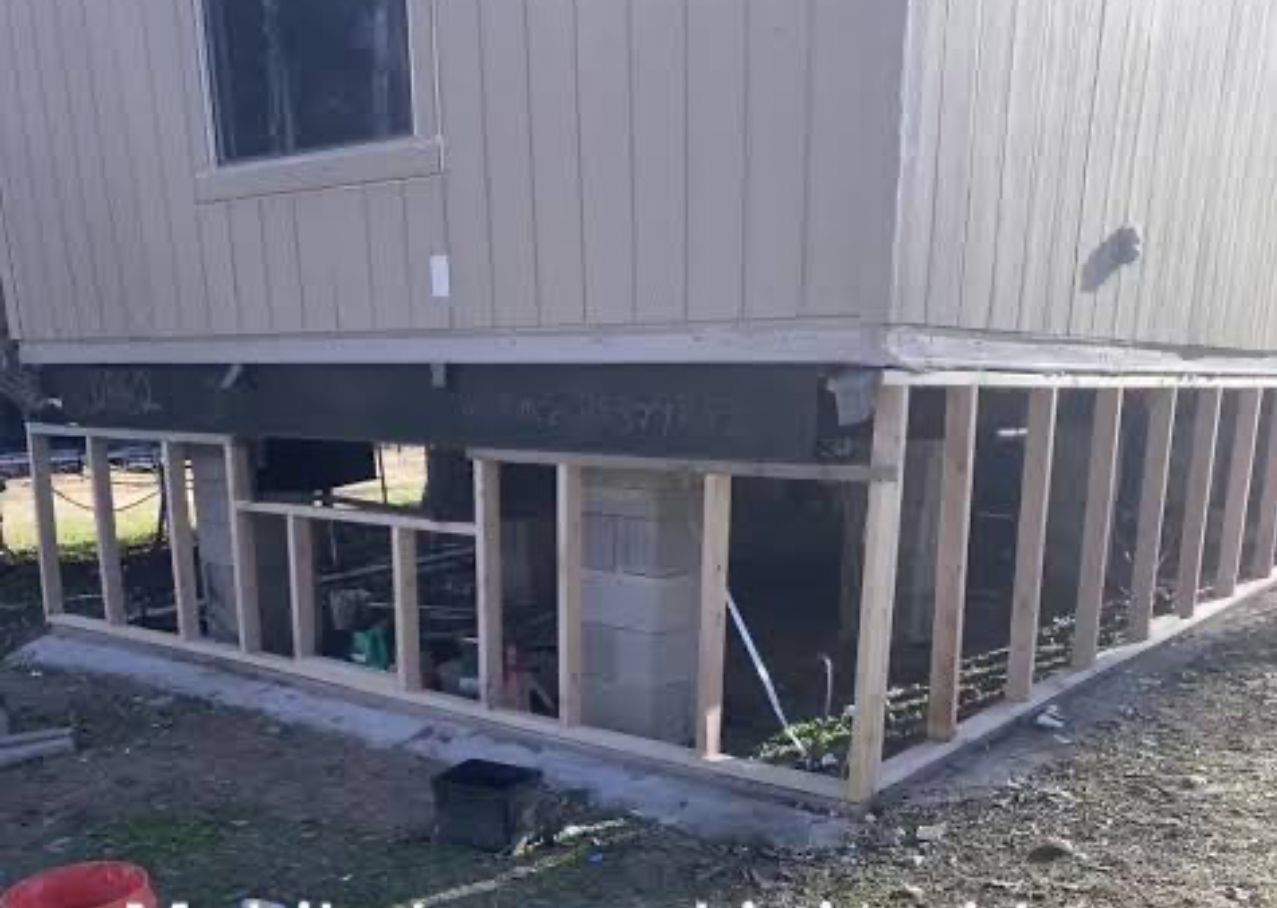 Construction site with a partially built basement and siding installation.