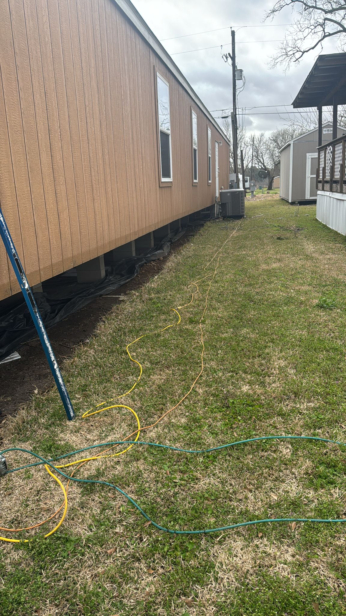 A yard with grass and a hose next to a raised building.
