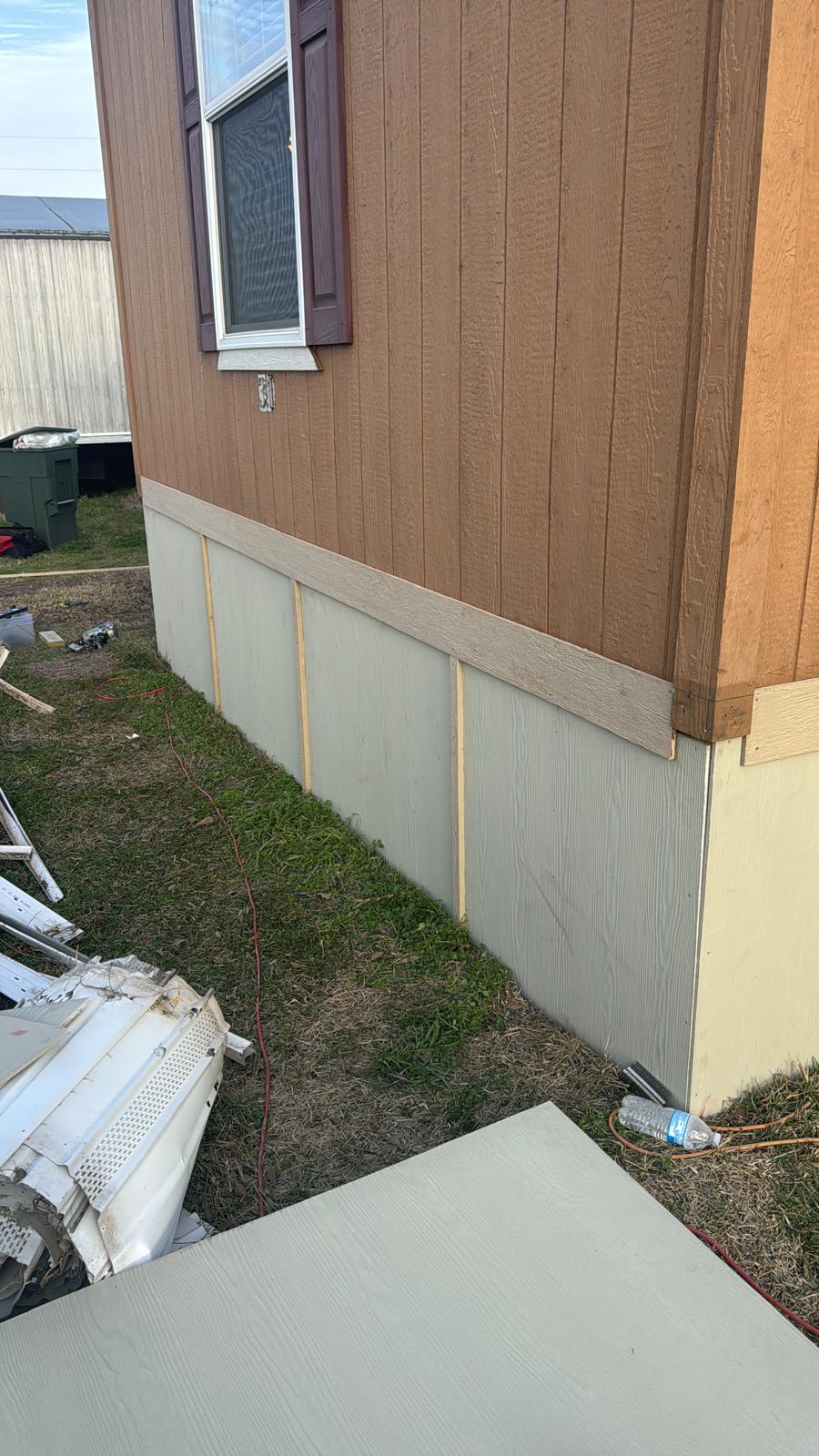 Concrete foundation with wood siding and grass beside a building.