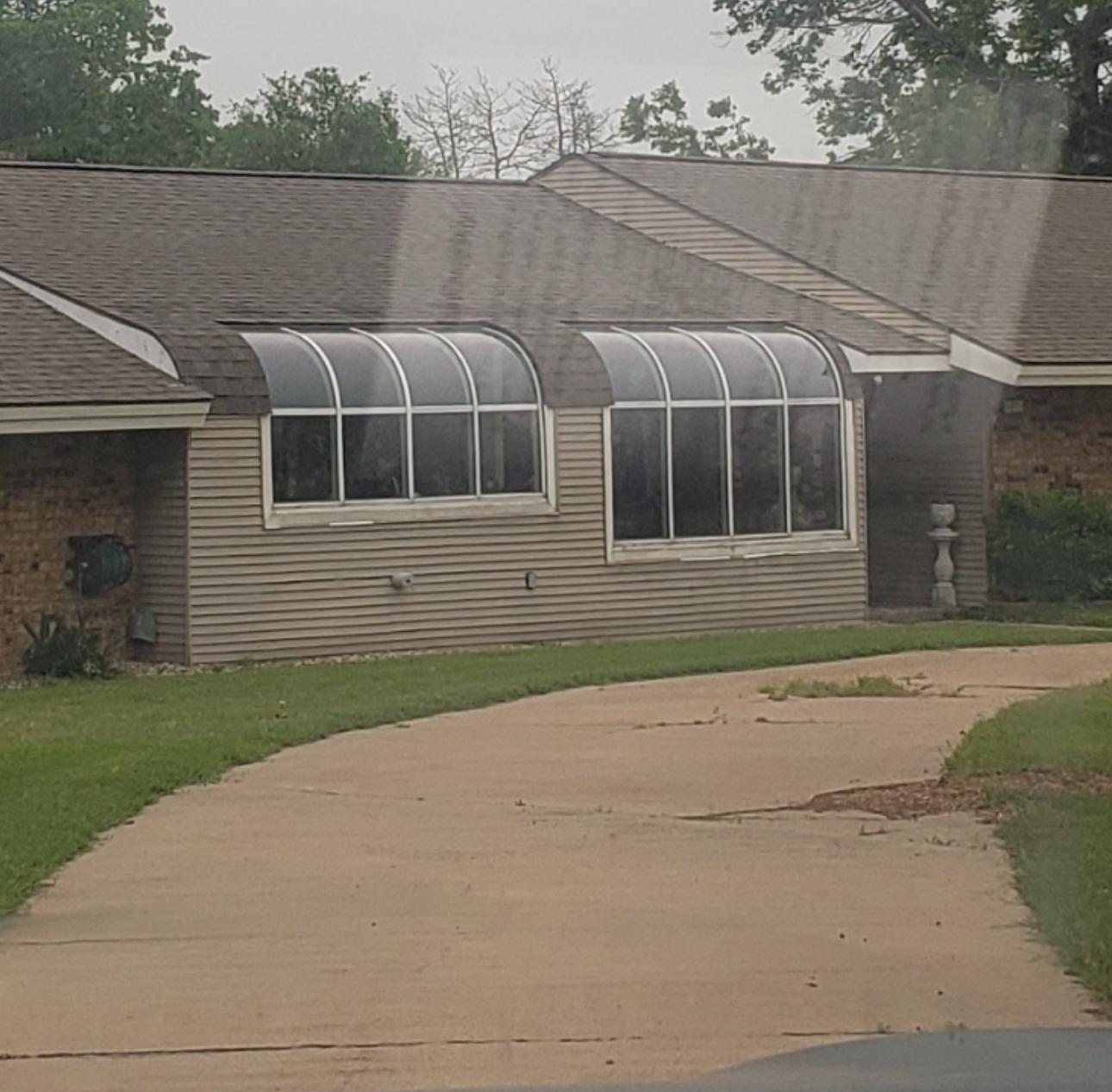 House with curved glass awnings over windows and door.