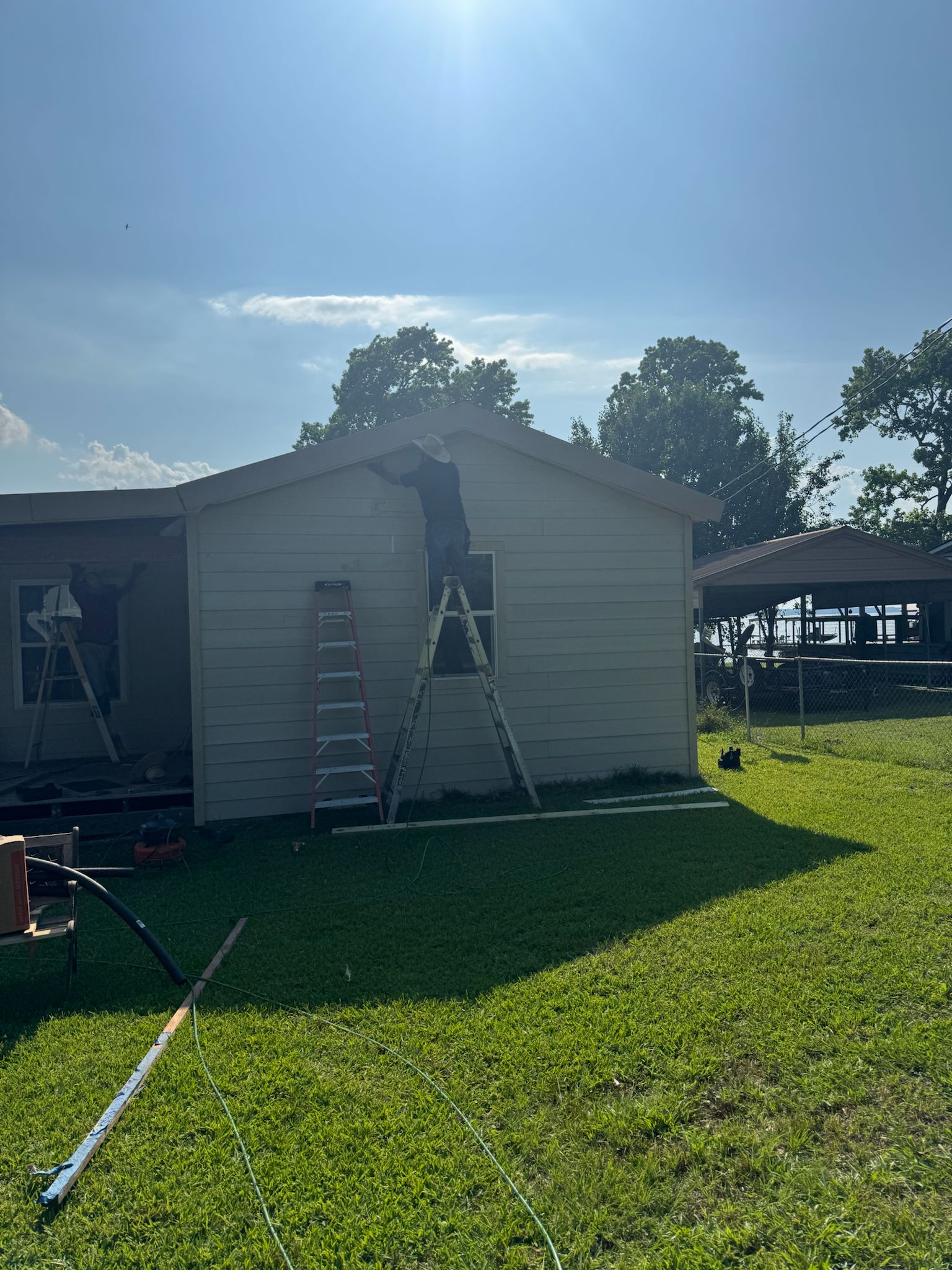 Workers repairing the exterior of a small house on a sunny day.