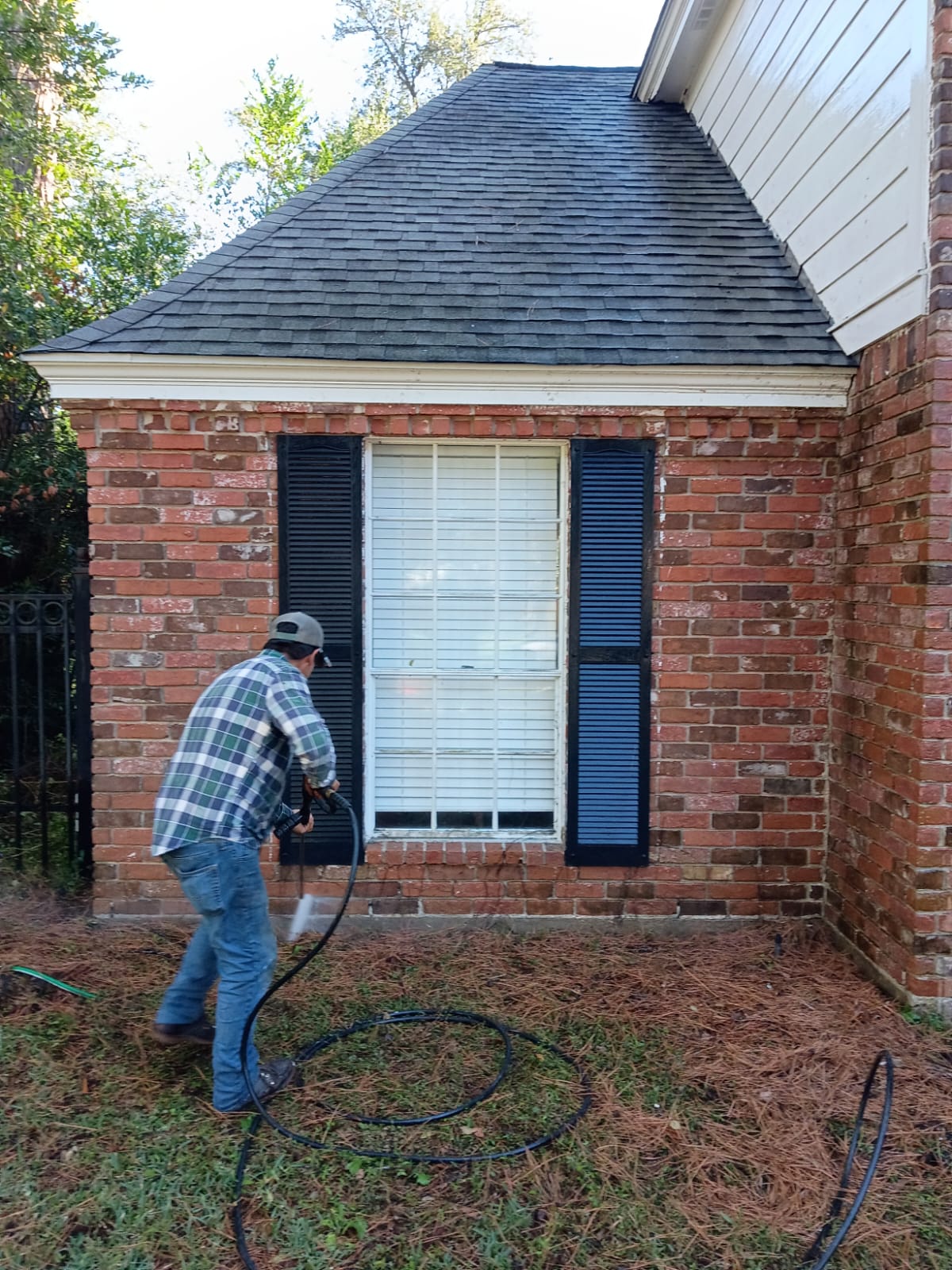 Person cleaning a house window with a pressure washer.