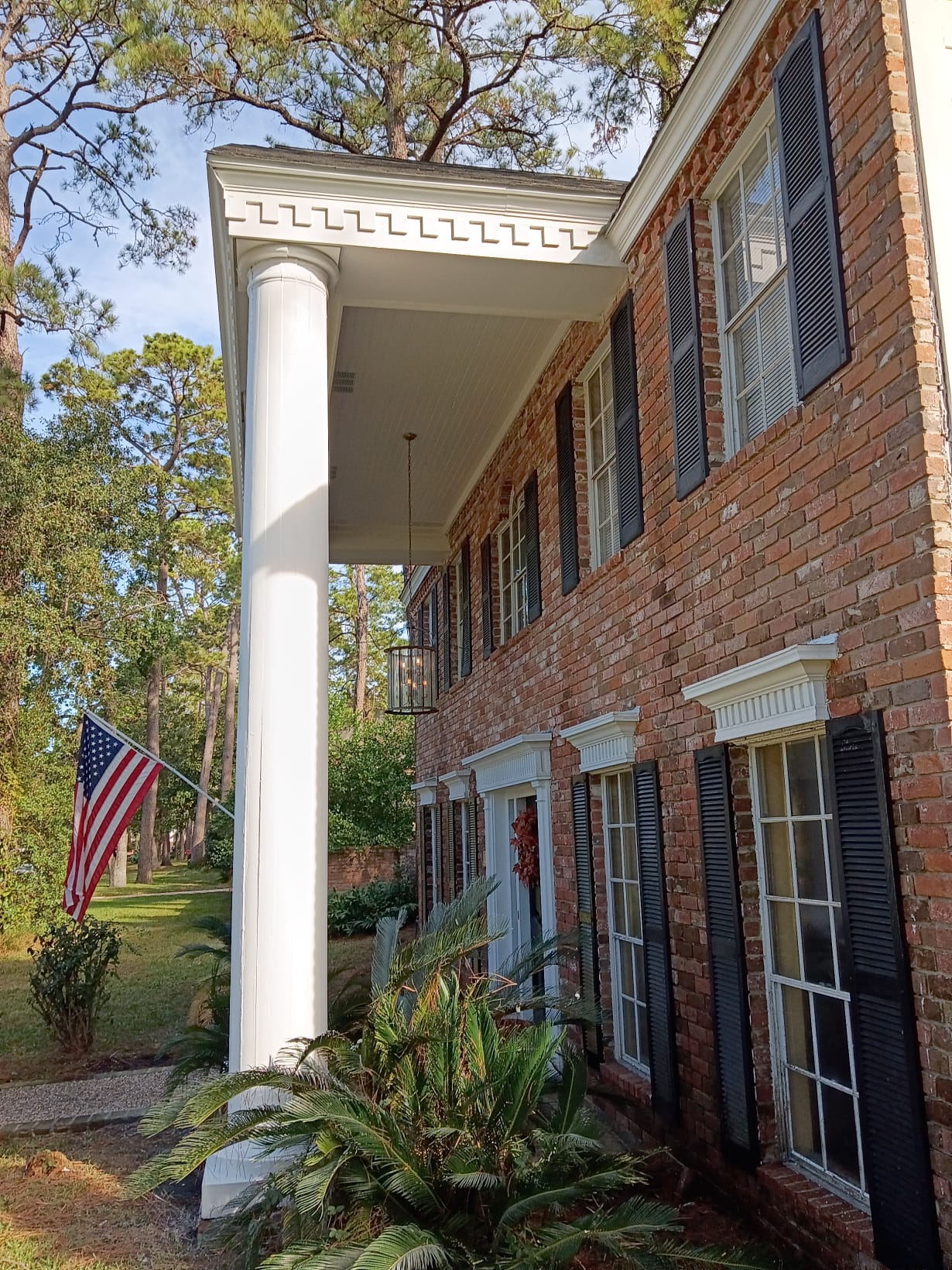 American flag by a brick house with tall white columns.