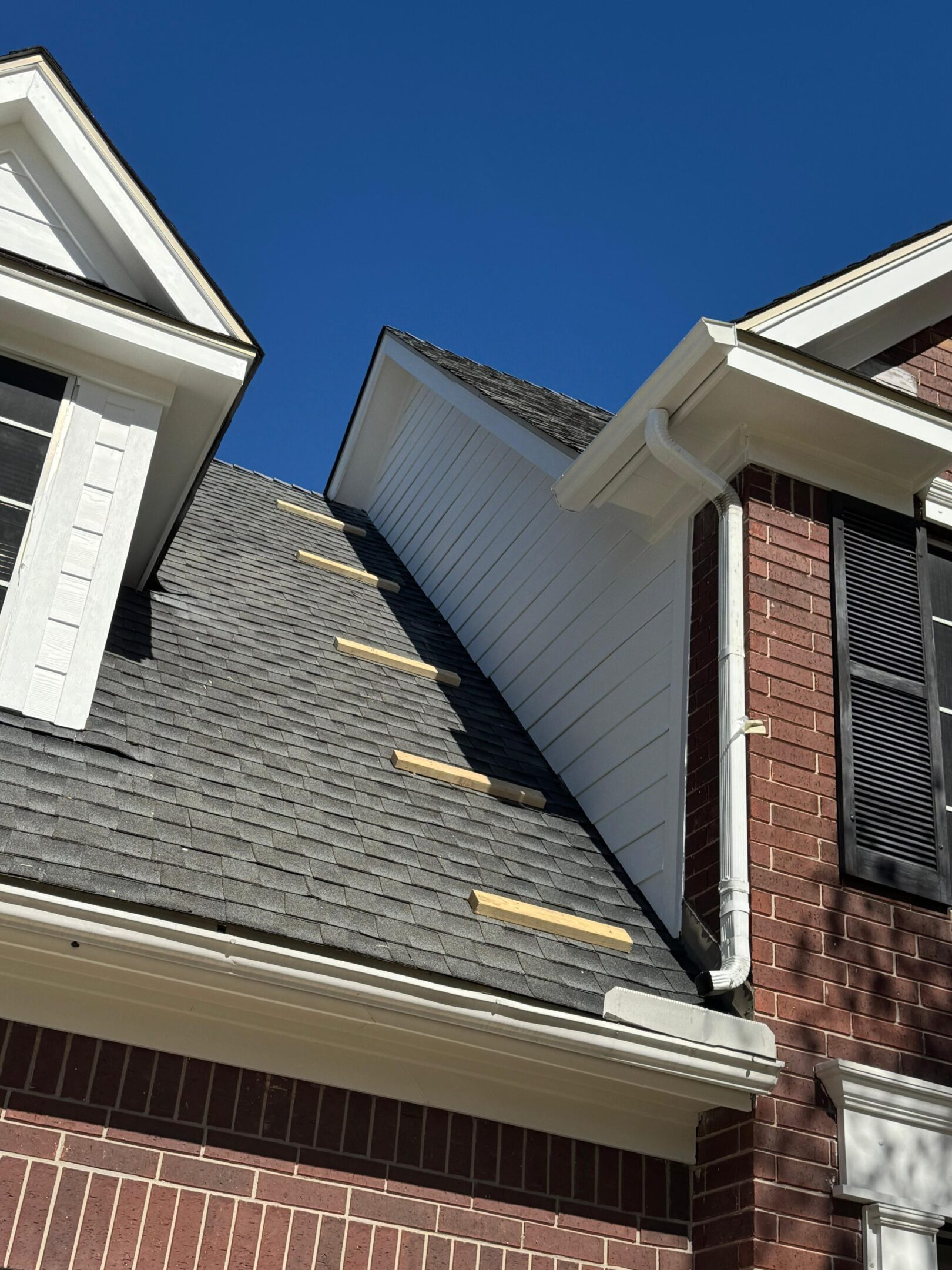 Roof repair work on a house under a clear blue sky.